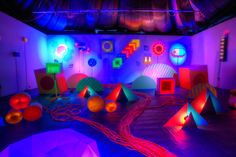 brightly lit room with various colored objects on the floor and lights in the ceiling,