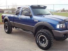 a blue pick up truck parked in a parking lot next to a chain link fence