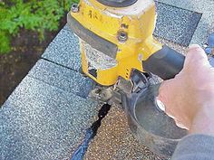 a person is using a yellow and black device on top of a roof