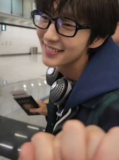 a young man wearing glasses and holding a cell phone