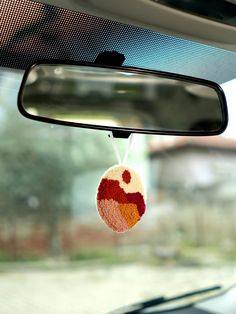 a car mirror hanging from the side of it's rear view mirror with a red and white ball on it