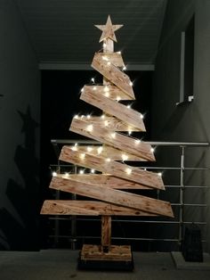 a wooden christmas tree with white lights on it's sides and a star hanging from the top