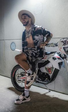 a man in a hat is sitting on a motorbike and posing for the camera