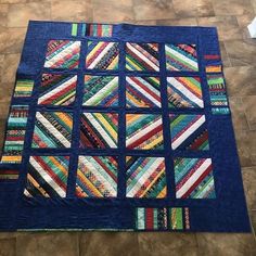 a patchwork quilt is on the floor in front of a tile floor with a blue background