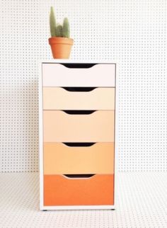 an orange and white dresser with a potted cactus in it's top drawer