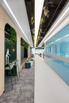 an office with plants growing on the wall and chairs in front of it, along with glass partitions