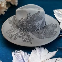 Wide Brim Hat in Grey, Burned Hat using Pyrography Techniques. All art is applied freehanded. Each Hat is a One of a Kind. Each Hat made by PIPER comes with a Macramé Wall Hat Hanger and Travel Bag. Hats are sealed for weather and wear. Hat Burning Ideas, Pyrography Techniques, Hat Burning Designs, Burning Hats, Burnt Hats, Cowboy Hat Crafts, Burned Hats, Hat Painting, Cowboy Hat Design