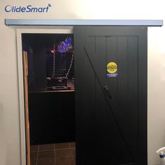 an open black door with a sign on it that says glide smart next to a white wall