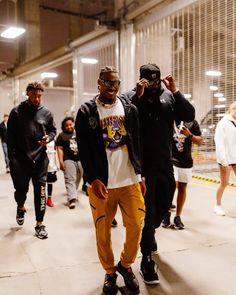 two men standing next to each other in front of a group of people wearing black and yellow outfits