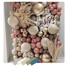 a happy birthday sign surrounded by balloons and other items in pastel colors on a white background