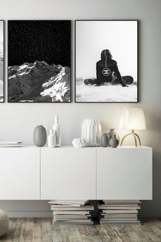 two black and white pictures hanging on the wall above a sideboard in a living room