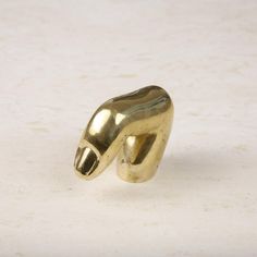 a gold colored ring with an animal's head sticking out of the middle, on a white surface