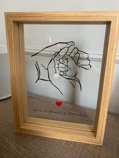 a hand holding a heart in a wooden frame