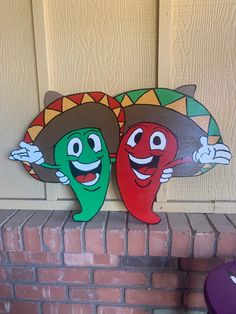 two chilis with sombreros on their heads are hanging from the front door