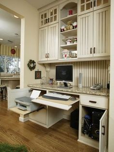 a home office with built - in desk and cabinets