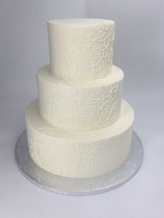 a three tiered white wedding cake sitting on top of a table