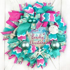 a wreath that has been decorated with pink and blue ribbon, starfish, and christmas ornaments