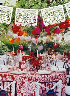 the table is set with red and white cloths, flowers, candles, and napkins