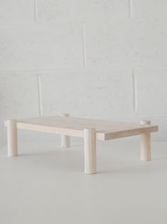 a small wooden table sitting on top of a white floor next to a brick wall