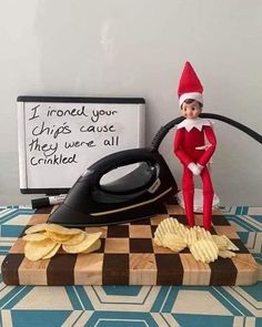 an elf is sitting on top of a table next to a black iron and chips