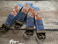 three blue and brown jeans with floral print on them, one has two metal hooks