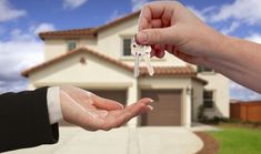 two people handing keys to each other in front of a house with a sky background