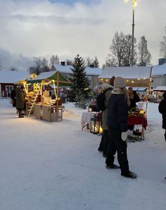 people are standing outside in the snow with christmas decorations on them and lights strung up