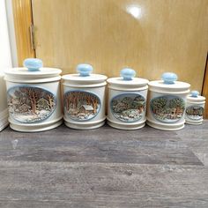 four ceramic canisters sitting on top of a wooden floor next to a door