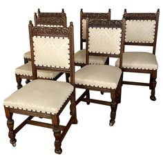 four wooden chairs with white upholstered cushions