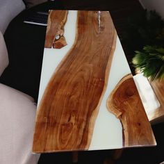 a table made out of wood and glass with a plant in the corner next to it