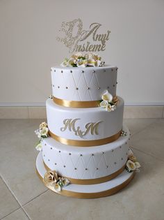 a three tiered wedding cake with gold trimmings and flowers on the side