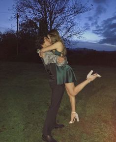 a man and woman standing in the grass with their arms around each other as they kiss