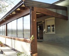 a house with a wooden roof and glass windows on the front porch, facing an empty street