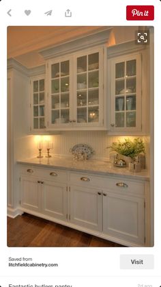 a kitchen with white cabinets and marble counter tops