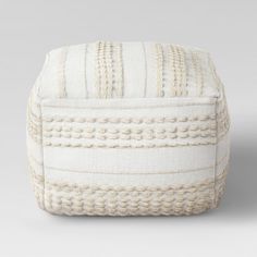 a white ottoman cushion with braiding on it