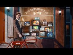 a man standing next to a red bicycle in front of a store window with an advertisement on it