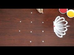 a cat is sitting on the floor next to some cups and a table with food