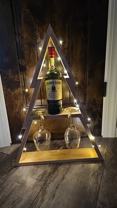 a bottle of jameson on top of two glasses in a triangle shaped display with lights