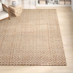 a living room area with a rug, chair and bookshelf on the floor