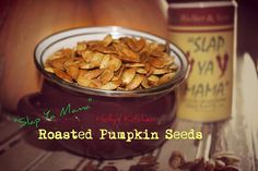 roasted pumpkin seeds in a glass bowl next to a bottle of maple syrup on a table