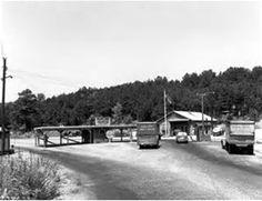 an old black and white photo of cars driving down the road with trees in the background