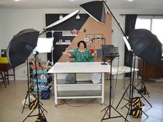 a woman sitting at a table surrounded by photography equipment