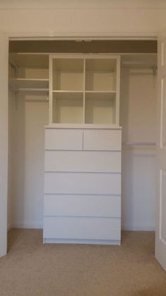 an empty closet with white cabinets and drawers