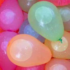 many different colored balloons with water droplets on them