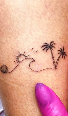 a woman's foot with a small palm tree and seashell tattoo on it