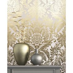 two silver vases sitting on top of a table next to a wallpapered background