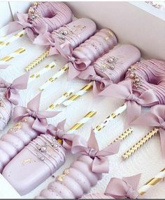 a box filled with lots of pink baby booties next to some gold and white sticks