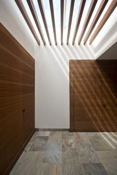 an empty room with wooden slats on the ceiling and doors in the wall to the left