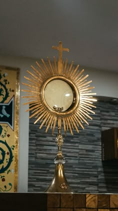 a golden clock with a cross on it and a mirror in the middle behind it