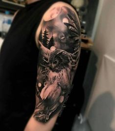 an owl and bird tattoo on the left arm, with trees in the back ground